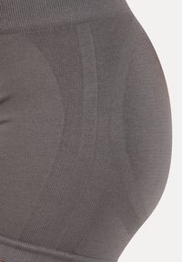 Gros plan d’un tissu gris sans couture avec des motifs de tricot côtelés et texturés formant des formes courbes.