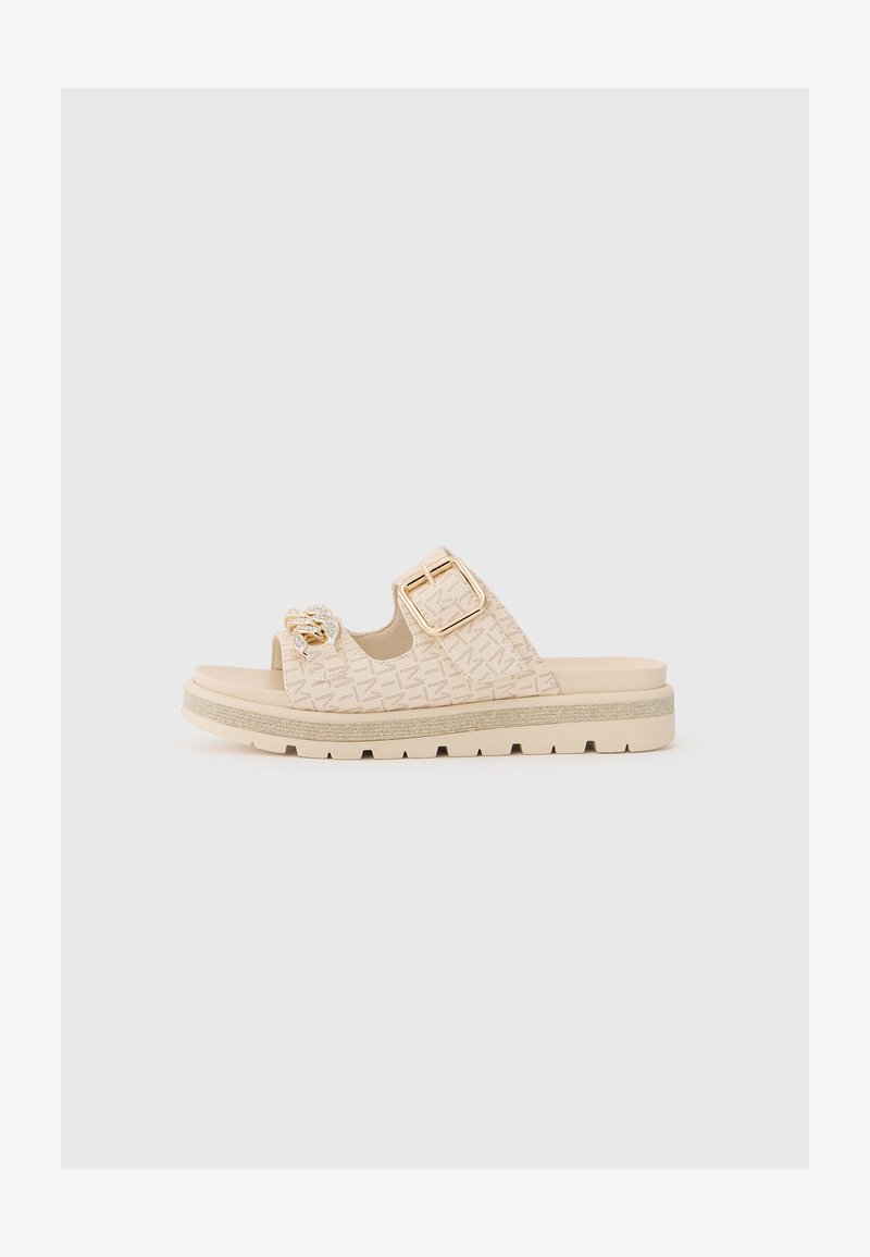 Μπεζ πέδιλο με ανάγλυφο σχέδιο, φαρδιές λουρίδες, χρυσό τόνο αγκράφα και διακοσμητικό στοιχείο. Υφασμάτινη σόλα για πρόσφυση και υποστήριξη.