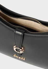 Pochette in ecopelle nera con finiture in oro, chiusura a cerniera, dettaglio con logo G e interno in tessuto beige con nome del marchio impresso.