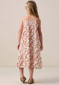 Blumenkleid aus Baumwolle mit Spaghettiträgern, gerafftem Oberteil, gestuftem Rock und Kirschmuster in Rosa-, Orange- und Brauntönen, kombiniert mit Sandalen.