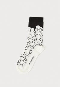 Calzini in bianco e nero con un motivo floreale su uno sfondo crema. Realizzati in tessuto morbido, con un bordo nero solido e un logo sulla punta.