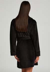 Svart, mjuk badrock med långa ärmar, midjeband och ribbade muddar. Mjuk textur och längd till mitten av låren. Ren, enkel design.