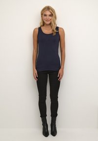 Tamsiai mėlynas talijas išryškinantis rankovių neturintis marškinėlis su apvalia iškirpte, derinamas su juodomis aptemptomis džinsomis ir juodais auliniais bateliais.