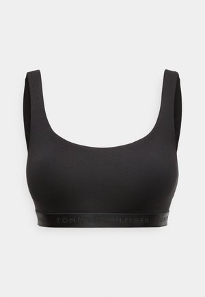 Reggiseno sportivo nero senza cuciture con spalline larghe e una fascia elastica in fondo con il logo Tommy Hilfiger discreto.