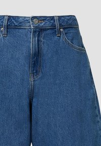 Zilā denima džinsi ar taisnu piegriezumu, augstu jostasvietu un kontrastējošiem diegiem. Iekļauta metāla pogu aizdare un priekšējās kabatas.