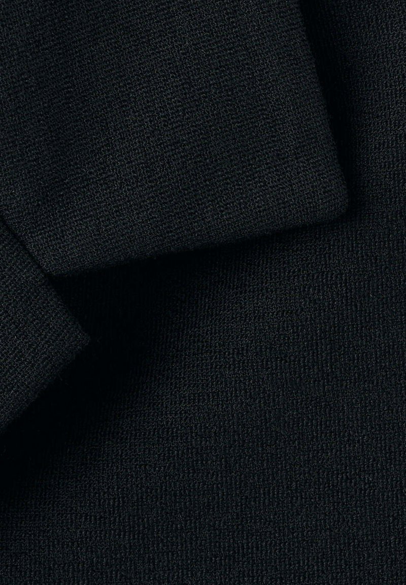 Primer plano de tela de punto negra con tejido texturizado visible y pliegues en capas.