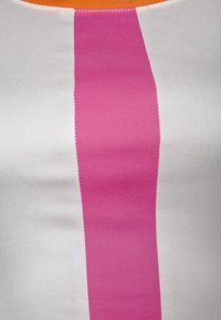 Topp utan ärmar i ett slätt tyg med en vit bas och ett framträdande rosa vertikalt rand samt en orange kant vid halsen.