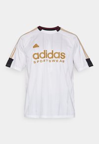 Balta Adidas sportinė marškinė su auksinėmis raidėmis, apvaliu kaklu, juodais akcentais ant rankovių ir subtiliomis vertikaliomis juostelėmis.