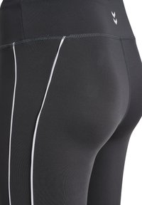 Black athletic leggings featuring a smooth texture, white side accents, and a fitted design. Top includes a simple logo near the waistband.