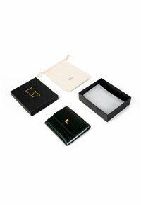 Portfel z ciemnozielonej skóry o wzorze krokodyla, z złotym zapięciem, w zestawie z beżowym woreczkiem na sznurek i czarnym pudełkiem na prezent.