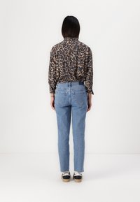 Leopardprint button-up shirt, blauwe high-waisted jeans en zwart-witte sneakers. Licht, textiel met een ontspannen pasvorm.