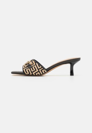 Sort åben tå mule sandal med beige geometrisk mønsterrem og lille sort hæl på hvid baggrund.