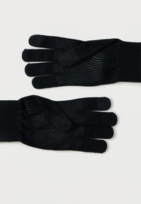 Guanti neri in maglia con punte texturizzate, dotati di motivi circolari concentrici sui palmi per una migliore presa e compatibilità con il touchscreen.