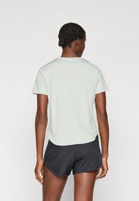 Svetlozelené športové tričko s okrúhlym výstrihom, krátkymi rukávmi a voľným strihom, skombinované s čiernymi šortkami s hladkou textúrou.