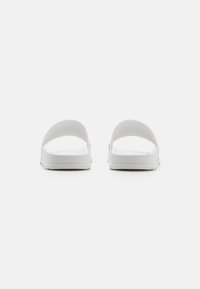 Hvide slide sandaler med flade såler, åben tå og uden hæl. Glat tekstur med en minimalistisk stil og uden synlige mønstre.