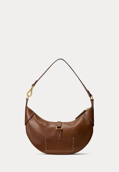 Brun læderhalvmåne-taske med øverste lynlås, guldspænde og enkelt skulderstrop mod en ensartet lys baggrund.