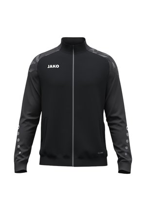 Zwarte sportjas met volledige rits, hoge kraag, wit JAKO-logo op de borst, patroon op de schouders en gestippeld ontwerp op de onderste mouwen.