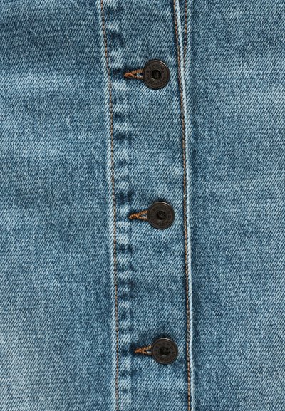 Κοντινό πλάνο μπλε τζιν υφάσματος με τρία ορατά μαύρα μεταλλικά κουμπιά, ραμμένα με καφέ κλωστή κατά μήκος μιας κάθετης ραφής.