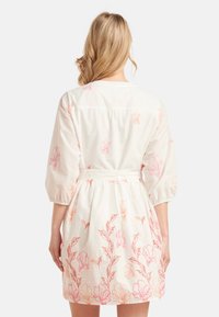White dress with pink floral embroidery, three-quarter puff sleeves, fitted waist, and gathered skirt. Soft fabric with light texture.