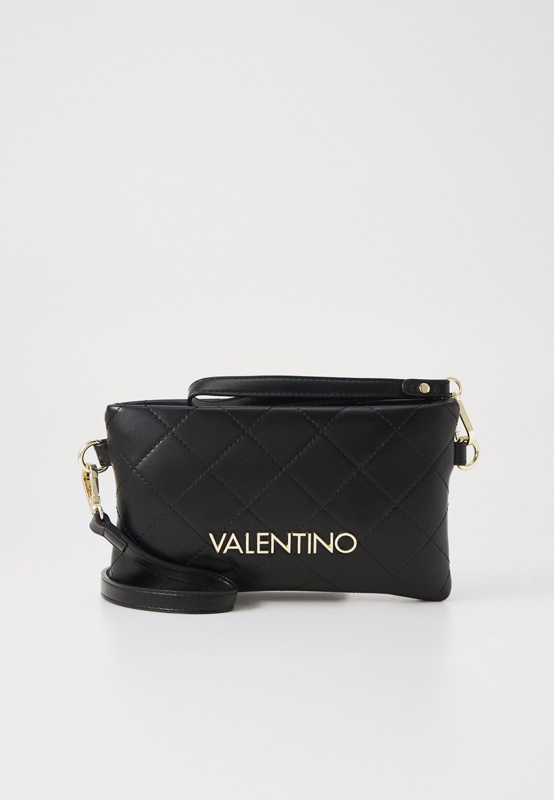 Černá prošívaná kožená spojka se zlatým logem. Obsahuje odnímatelný popruh a hladký povrch. Kompaktní obdélníkový tvar.