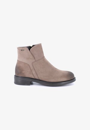 Stivaletti in suede taupe con punta tonda, tacco basso impilato e chiusura con zip laterale; caratterizzati da cuciture minime e una texture a gradiente sottile.