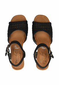 Czarne plecione sandały z teksturowaną cholewką, regulowanym paskiem na kostce i brązową wkładką z sztucznej skóry. Posiadają płaską podeszwę.