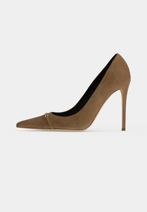 Escarpin femme en daim marron à talon haut, bout pointu et talon aiguille fin sur un fond clair uni.