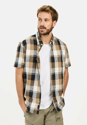 Korte mouwen geruit shirt met een brown, witte en marineblauwe dambordpatroon, knoopsluiting en een relaxte pasvorm over een wit T-shirt.