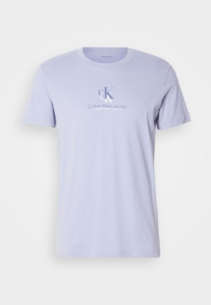 T-shirt en coton violet clair avec un col rond et des manches courtes. Le logo centré indique "Calvin Klein Jeans" dans un design contrasté.