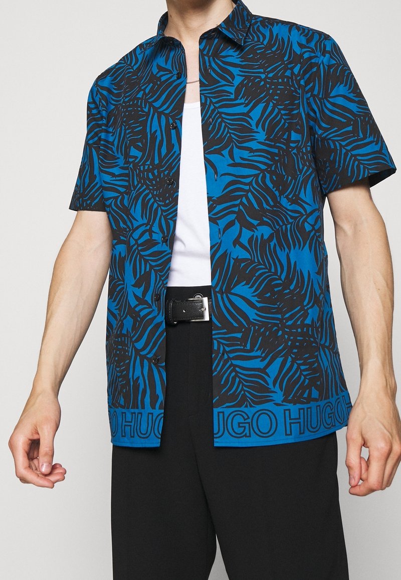 Korte mouw knoopshirt in het blauw met een zwart bladerenpatroon, voorzien van een kraag en "HUGO" branding aan de zoom. Gladde stoftextuur.
