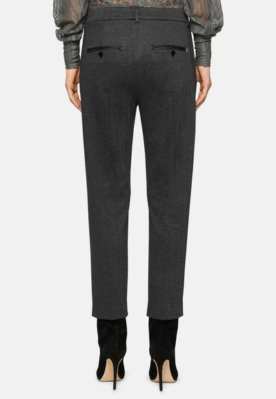 Pantalons gris ajustés en tissu texturé, coupe slim, avec des poches arrière zippées. Associés à des chaussures à talons hauts noires.