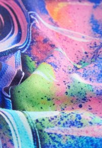 Kleurrijke stof met een gladde textuur, voorzien van een levendig abstract patroon in roze, groen, blauw en oranje tinten, vermengd met gespikkelde details.