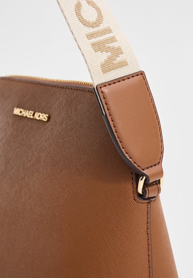 Sac à main en cuir marron avec une finition texturée, doté d'une bandoulière en tissu avec imprimé logo et de détails en métal doré. Détail de fermeture éclair visible.