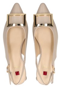 Tacones slingback beige con puntera en punta, detalle de hebilla cuadrada dorada, textura de cuero suave y un acento rojo en la plantilla.