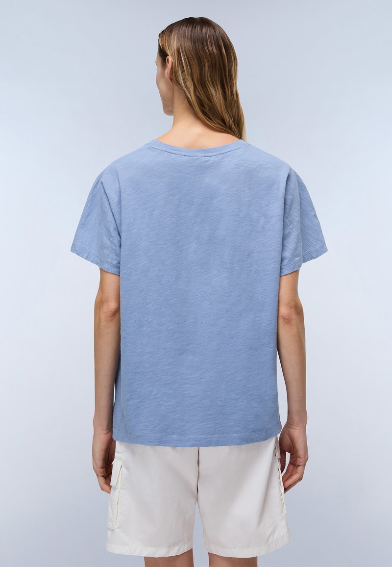 Helles blauer Baumwoll-T-Shirt mit bequemem Schnitt und kurzen Ärmeln. Verfügt über einen runden Halsausschnitt und einen flachen Saum, getragen mit weißen Shorts.