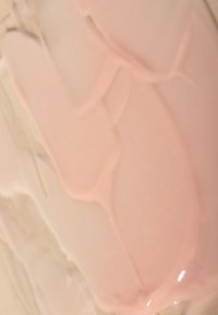 Krämig yta med nyanser av ljusrosa och beige, med en slät textur och glänsande yta, som visar lager och variationer i färg.