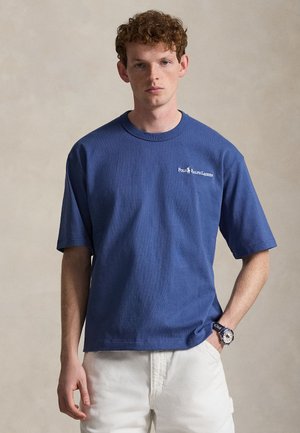 Μπλε βαμβακερό T-shirt με στρογγυλή λαιμόκοψη και κοντά μανίκια, με λευκό κεντητό λογότυπο στο στήθος. Χαλαρή εφαρμογή για άνεση.