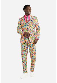 Completo colorato con motivo a pois di diverse dimensioni. Include una camicia rosa e una cravatta coordinata, completato da sneakers bianche.