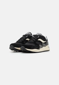 Black and gray athletic shoes featuring a combination of suede and mesh materials, with a textured sole and contrasting cream midsole.