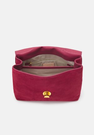 Open kleine magenta suède handtas met beige interieur, ritssluitingvak en gouden draaisluiting aan de voorkant.
