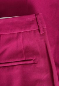 Magenta kalhoty na míru s plochým předním dílem, sklady a bočními kapsami, vyrobené z hladkého materiálu s mírně texturovaným vzhledem.