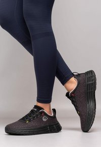 Grau und schwarze Sportschuhe mit einer strukturierten Oberfläche, runder Zehenpartie, niedrigem Profil und bunten Ösen. Die dicke Sohle bietet Polsterung und Unterstützung.