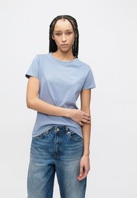 Γαλάζια κοντομάνικη μπλούζα με στρογγυλή λαιμόκοψη και μικρό λογότυπο "BOSS" στο στήθος, συνδυασμένη με ψηλόμεσα μπλε τζιν.