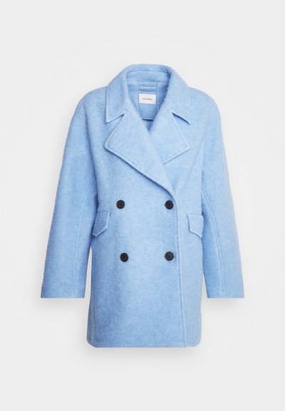 Manteau double boutonnage bleu clair en tissu texturé. Présente de grands boutons noirs, des revers pointus et deux poches avant. Manches courtes.