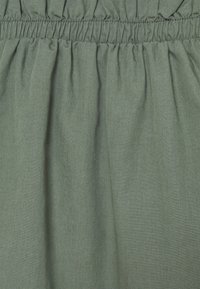 Gonna con elastico in vita in tessuto verde smorzato, caratterizzata da una texture arricciata e una superficie liscia e morbida. Design semplice e fluido.