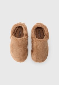 Et par brune, fuzzy slip-on tøfler med lukkede tær og "Crocs"-logo innvendig, vist fra toppen på en hvit bakgrunn.