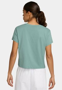 T-shirt cropped a maniche corte in morbido tessuto teal, presenta una scollatura rotonda e una vestibilità rilassata, mostrata da dietro con una texture liscia.