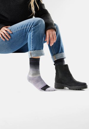Flerfärgade ankelsockor med lila och grå ränder, i kombination med svarta ankelstövlar. Blandet material av bomull, medel tjocklek och subtila mönster.