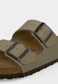 Κοντινό πλάνο μπεζ σανδάλι Birkenstock με δύο ρυθμιζόμενους ιμάντες με αγκράφες και ορατό φελλό πάτο.