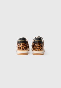 Paire de baskets à imprimé léopard avec languettes de talon noires et semelles blanches vues de dos sur un fond clair uni.